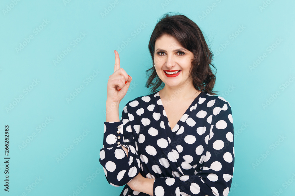 Smiling woman on a blue background pointing something by her finger Smiling woman on a blue background pointing something by her finger