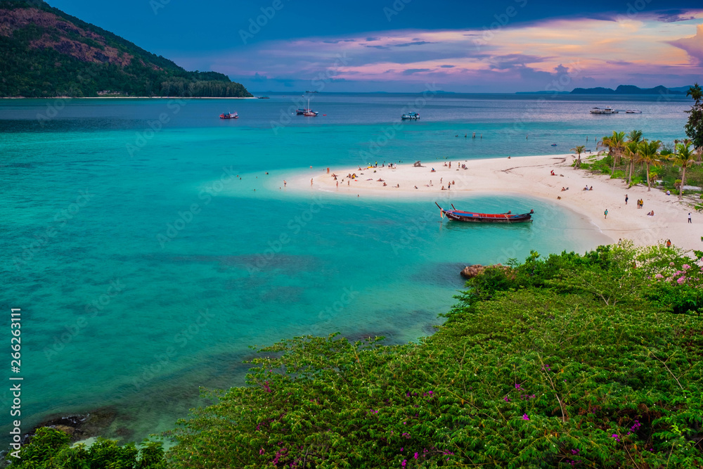 Beach that extends into the sea Looking out to see the island And blue sky There are many boats floating in the emerald green sea of the Andaman Sea. At Sunrise Beach, Koh Lipe, Satun, Thailand
