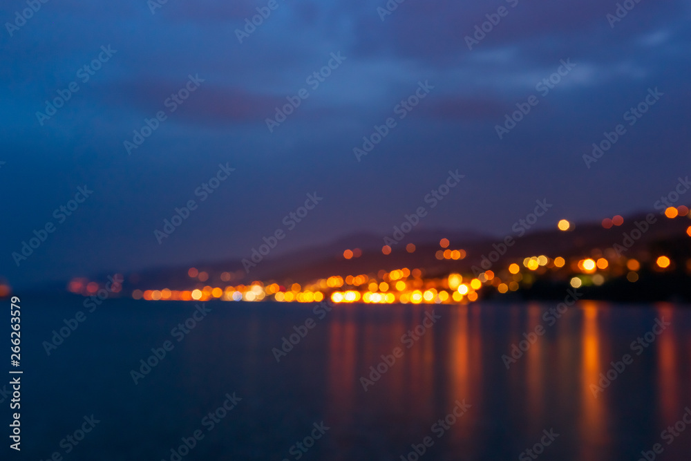 Blurred cityscape with  light bokeh and sea