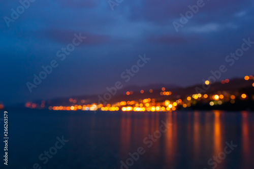 Blurred cityscape with light bokeh and sea