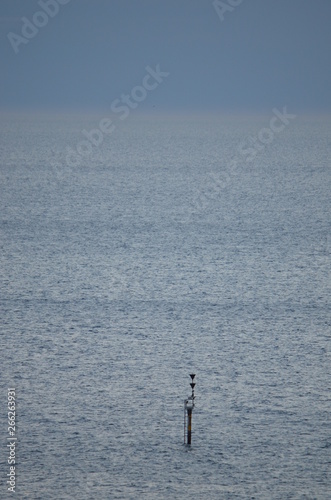 Seascape disappearing into misty clouds on the horizon with a navigatio0on marker off the beach at Glenelg South Australia