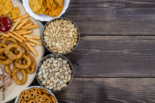 Mix of snacks for beer on dark wooden background. Top view. Empty space for text