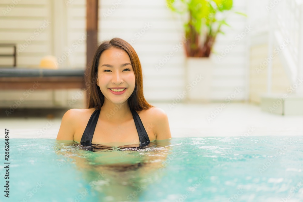 Portrait beautiful young asian woman smile happy relax around swimming pool in hotel resort for leisure