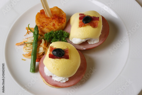 Eggs Benedict is an American breakfast that consists of two halves of an English muffin topped with a poached egg, bacon or ham, and hollandaise sauce. The dish was first popularized in New York City. photo