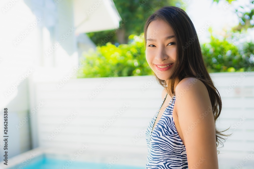 Portrait beautiful young asian woman smile happy relax around swimming pool in hotel resort for leisure