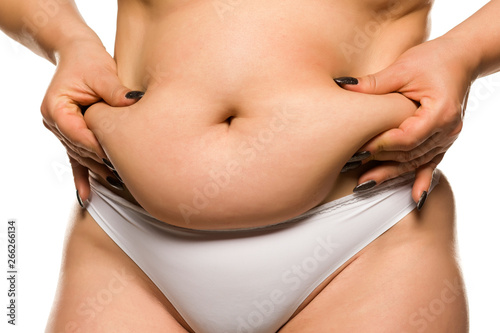 a fat woman pinching her belly on white background