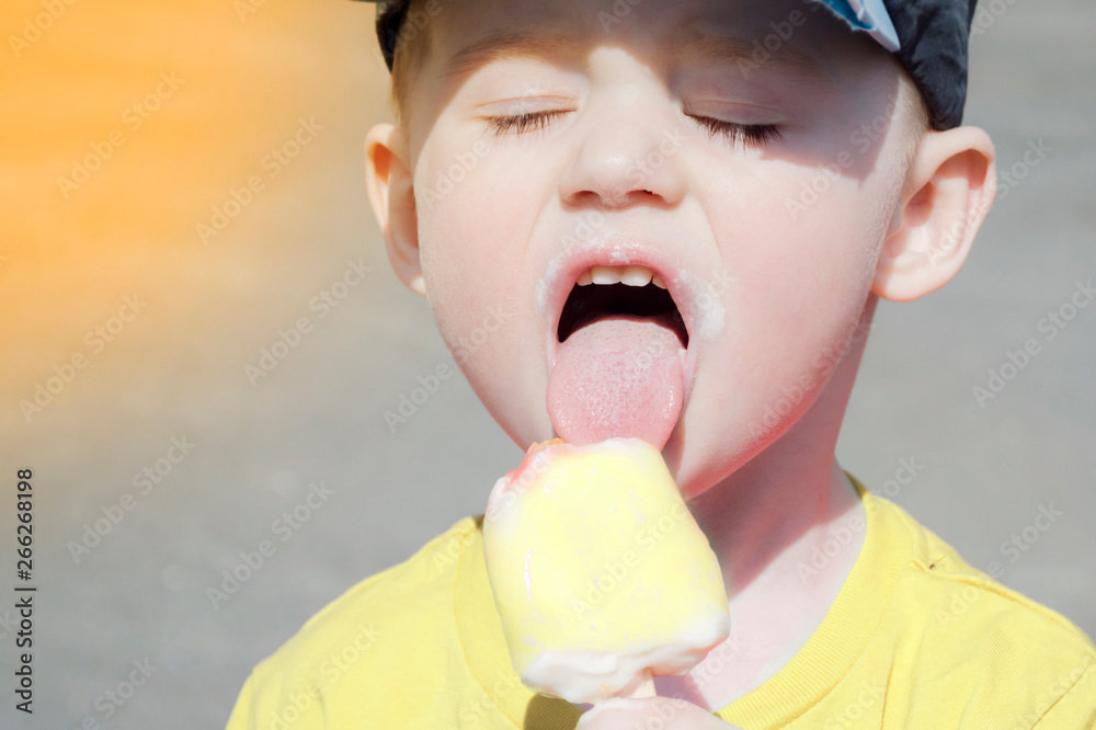 portrait of a child who eat ice cream on a warm summer day. boy in a baseball cap and the sun is shining, close-up face portrait of a child who eat ice cream on a warm summer day. boy in a baseball cap and the sun is shining, close-up face