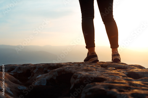 Unrecognizable young success woman hiker legs on mountain peak rock, rear view. Concept achieving goal, beginning of the path, travel, adventure, sport