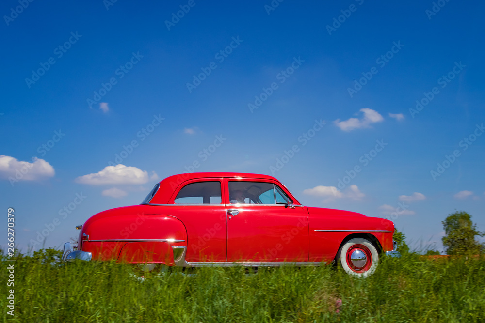 Side view of an elegant classic oldtimer american car on a rural street at morning sunlight Side view of an elegant classic oldtimer american car on a rural street at morning sunlight