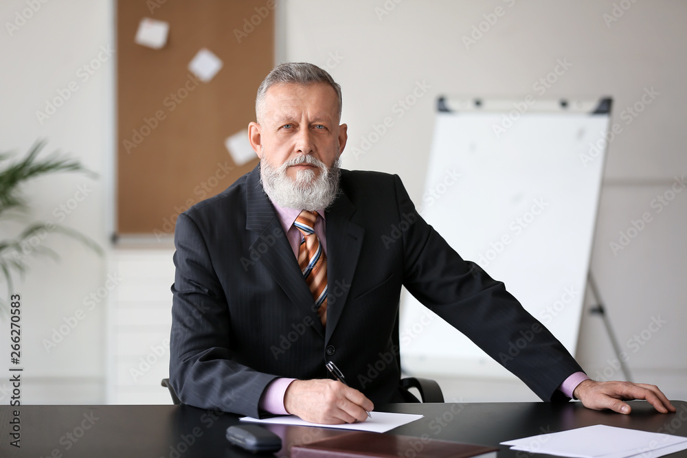 Mature businessman sitting at table in office Mature businessman sitting at table in office