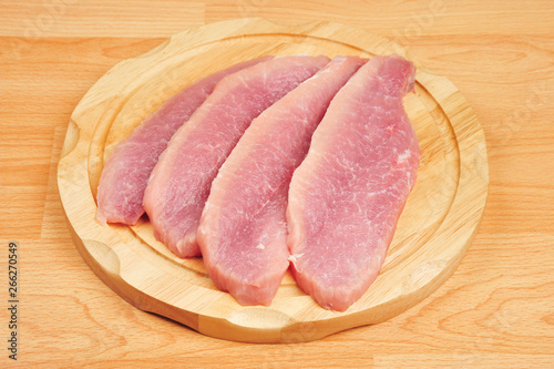 Raw pork meat sliced on a board, on an isolated wooden background