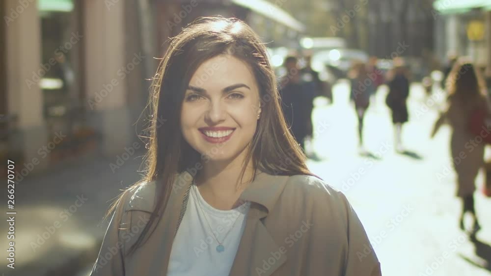 Beautiful smiling brunette girl looking to camera on the sunny street, urban portrait Beautiful smiling brunette girl looking to camera on the sunny street, urban portrait