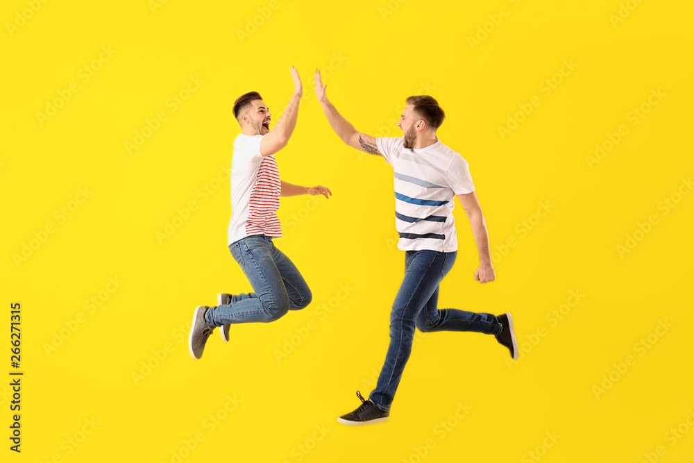 Jumping young men on color background - obrazy, fototapety, plakaty 