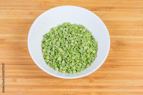 Green split peas in bowl on a wooden surface
