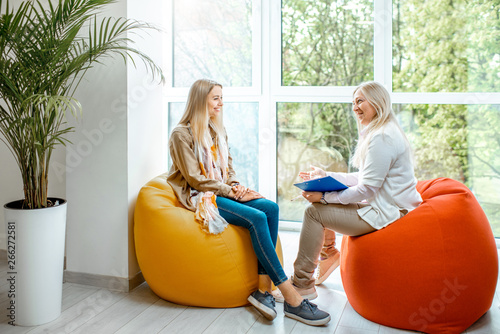 Obraz na plátně Young woman with senior female psychologist or mental coach sitting on the comfo
