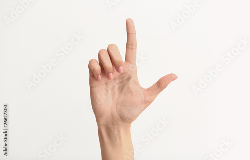 Female hand showing letter L on light background