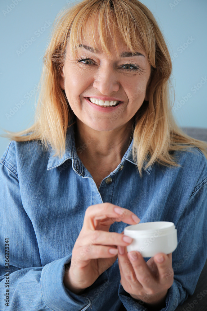 Mature woman with jar of cream on color background Mature woman with jar of cream on color background