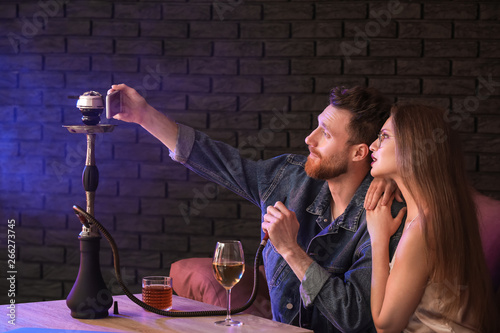 Young couple smoking hookah in cafe