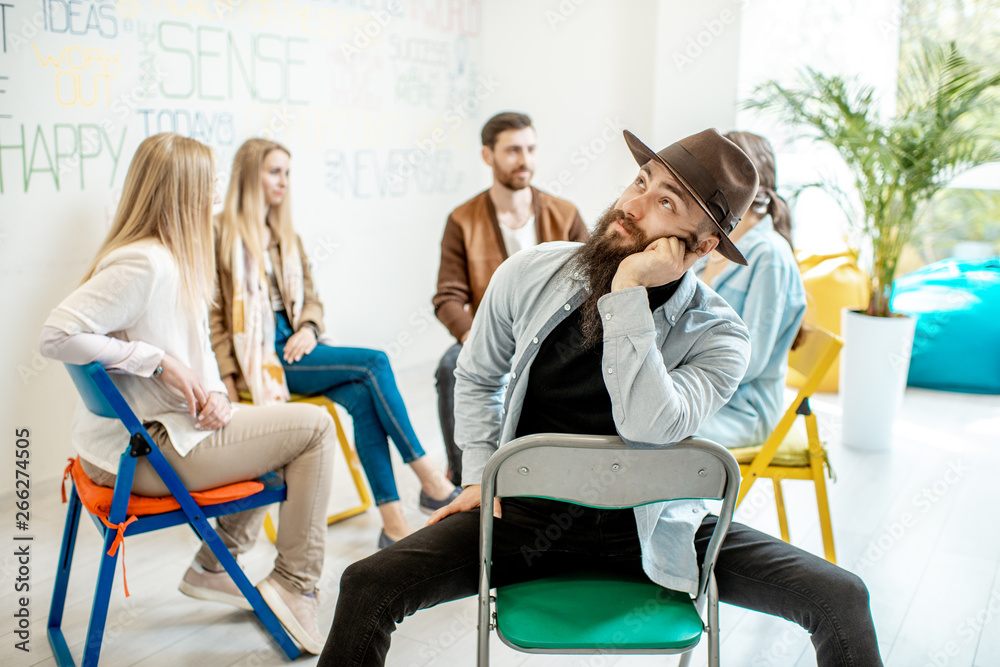 Portrait of a handsome man sitting in a circle with group of people during  the psychological training in the white office Stock Photo | Adobe Stock