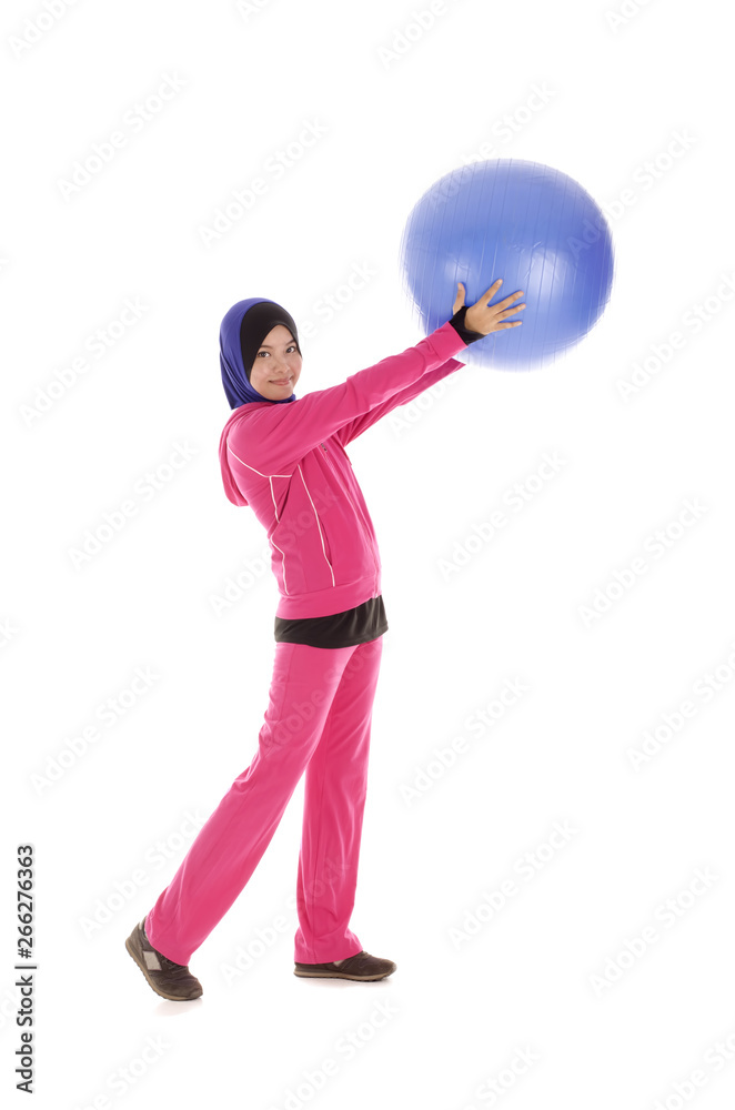 Young fitness muslimah holding a blue ball isolated on white