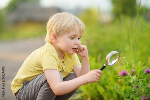 Kid exploring nature with magnifying glass. Close up.