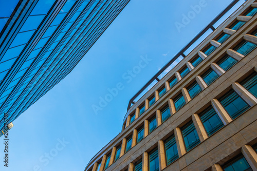 Bottom view on Glass wall in modern architecture skyscrapers in business center district against blue sky. Success element. Background for cover presentation design 