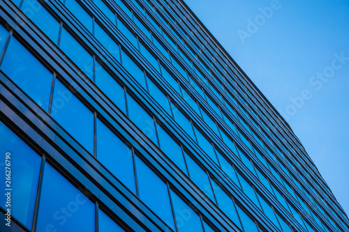 Bottom view on Glass wall in modern architecture skyscrapers in business center district against blue sky. Success element. Background for cover presentation design