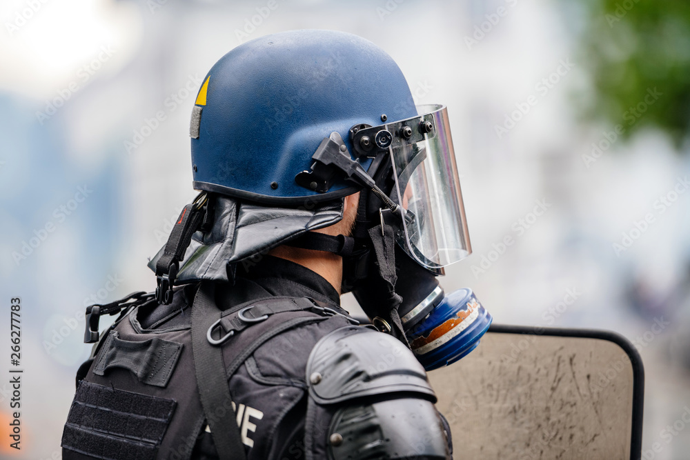 Rear view of police officer wearing gas mask against tear gas at protest  with Yellow jackets Gilets Jaunes Photos | Adobe Stock