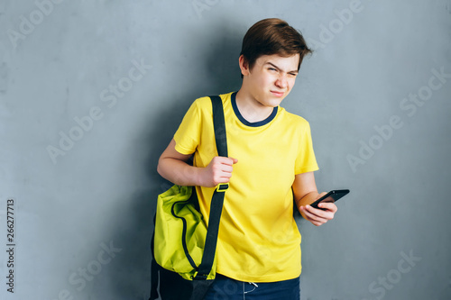 Guy in the yellow t-shirt on his shoulder sport bag uses the phone
