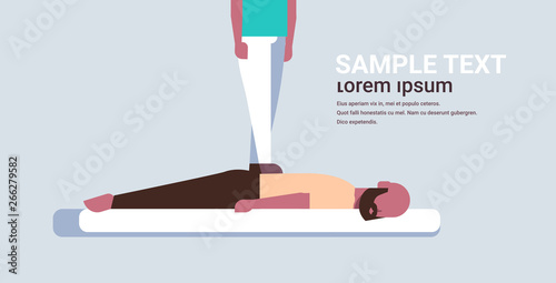 masseuse standing on patient's back doing healing treatment african american guy relaxing lying on table man having massage medical clinic manual therapy concept horizontal copy space