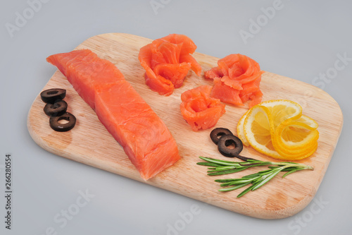 Fresh salmon decorative roses fillets, with lemon, olives on the board. Isolated on a gray background photo