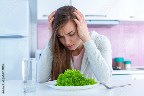 Sad unhappy woman is tired of dieting and not wanting to eat organic, clean healthy diet food