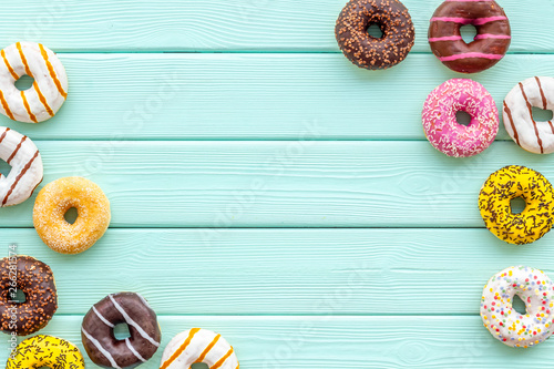 Donuts of different flavors for breakfast on mint green wooden background top view space for text