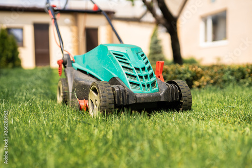 Lawn mower on the plot with green grass