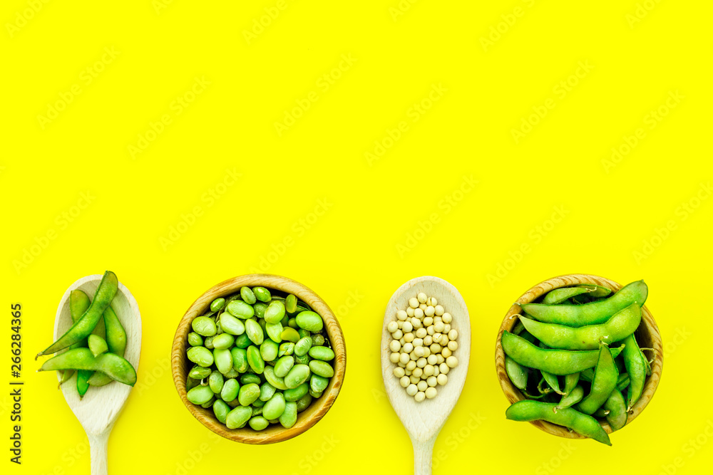 Edamame in bowl and spoon on yellow background top view mock up