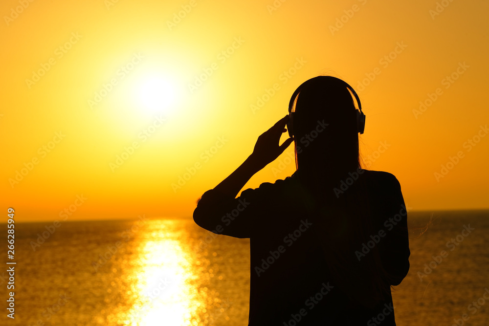 Silhouette of a woman listening to music at sunset