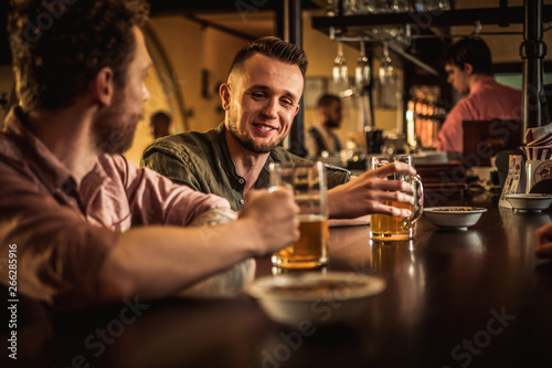 Cheerful friends drinking draft beer in a pub