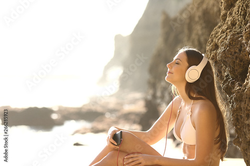 Relaxed sunbather listens to music on the beach #266285923