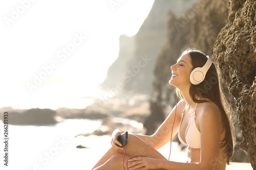 Relaxed tourist in bikini listening to music on the beach photo