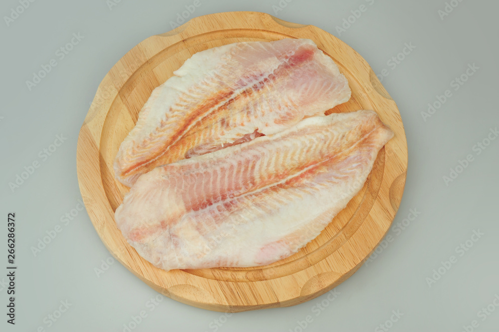 Pangasius fillet meat on a board on gray isolated background Pangasius fillet meat on a board on gray isolated background