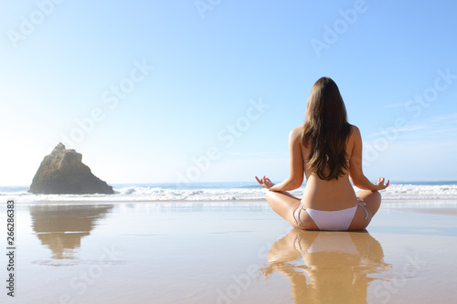 Back view of a woman in bikini doing yoga exercise