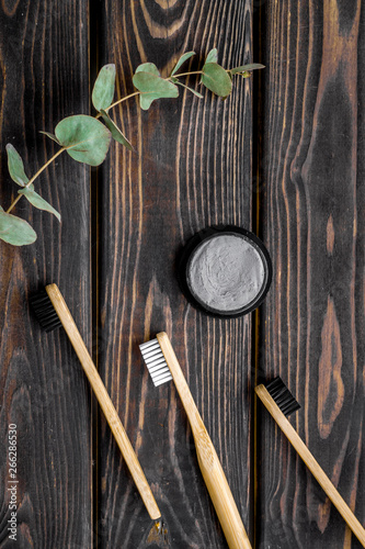 Eco materials concept with bamboo tooth brush and toothpaste with bamboo carbon on wooden background top view