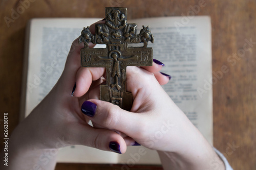 Religion. female hands with a cross on the background of the Bible, close-up
