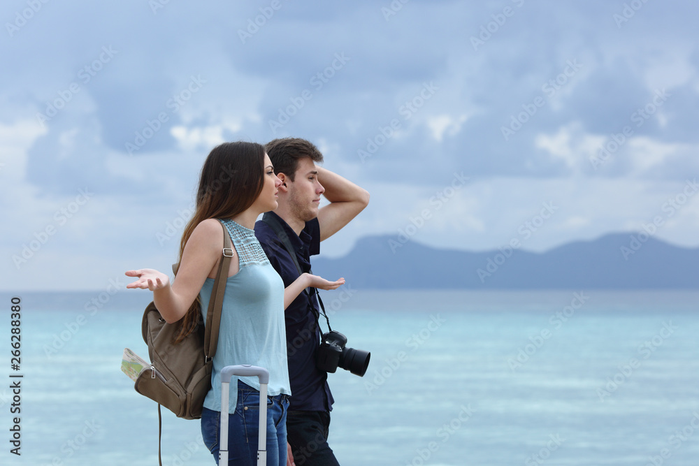 Angry couple complaining on a cloudy vacation Angry couple complaining on a cloudy vacation