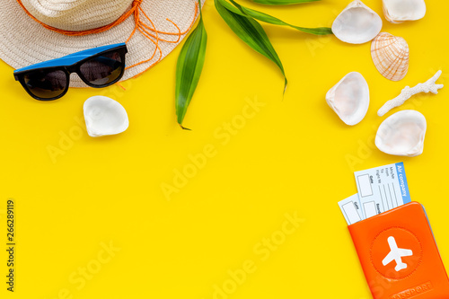 Summer travaling to the sea with straw hat, sun glasses, tickets and passport on yellow background top view mock up photo