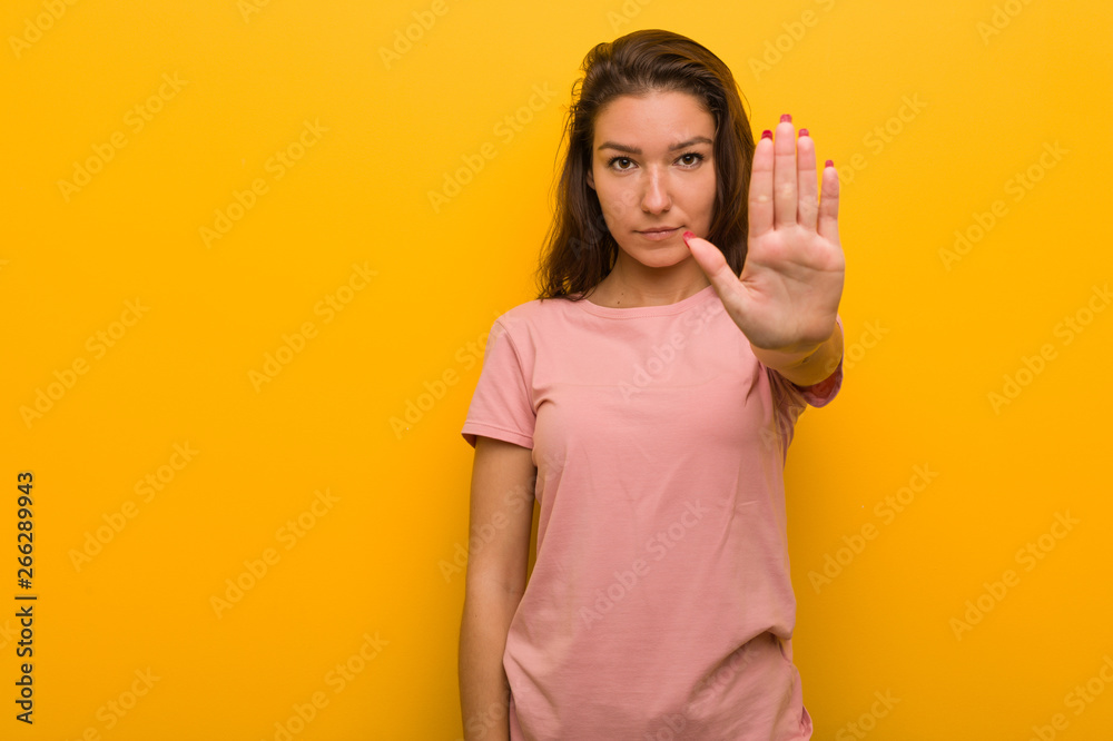 Young european woman isolated over yellow background standing with outstretched hand showing stop sign, preventing you. Young european woman isolated over yellow background standing with outstretched hand showing stop sign, preventing you.