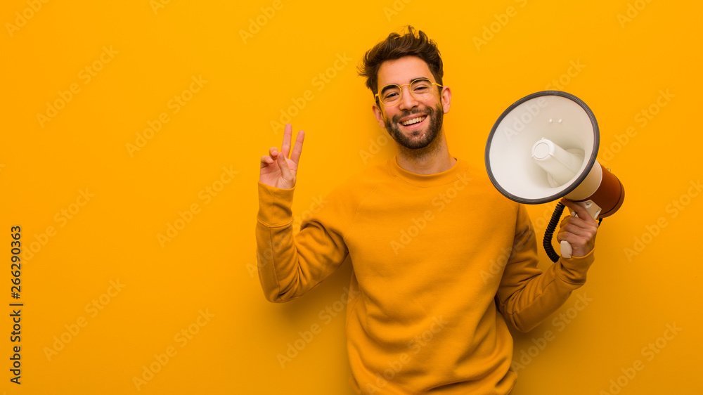 Young man holding a megaphone doing a gesture of victory Young man holding a megaphone doing a gesture of victory