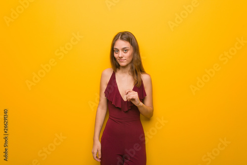 Young natural woman wearing a red dress against an orange wall