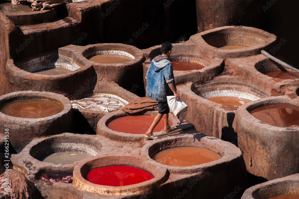 Blurred image of factory Tanneries of Fes, old big tanks of the Fez's tanneries with workers who working in a tannery on traditional craft leather dying. Morocco, Africa Blurred image of factory Tanneries of Fes, old big tanks of the Fez's tanneries with workers who working in a tannery on traditional craft leather dying. Morocco, Africa
