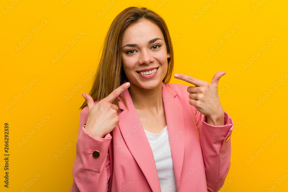 © Asier - Young fashion business woman smiles, pointing fingers at mouth.